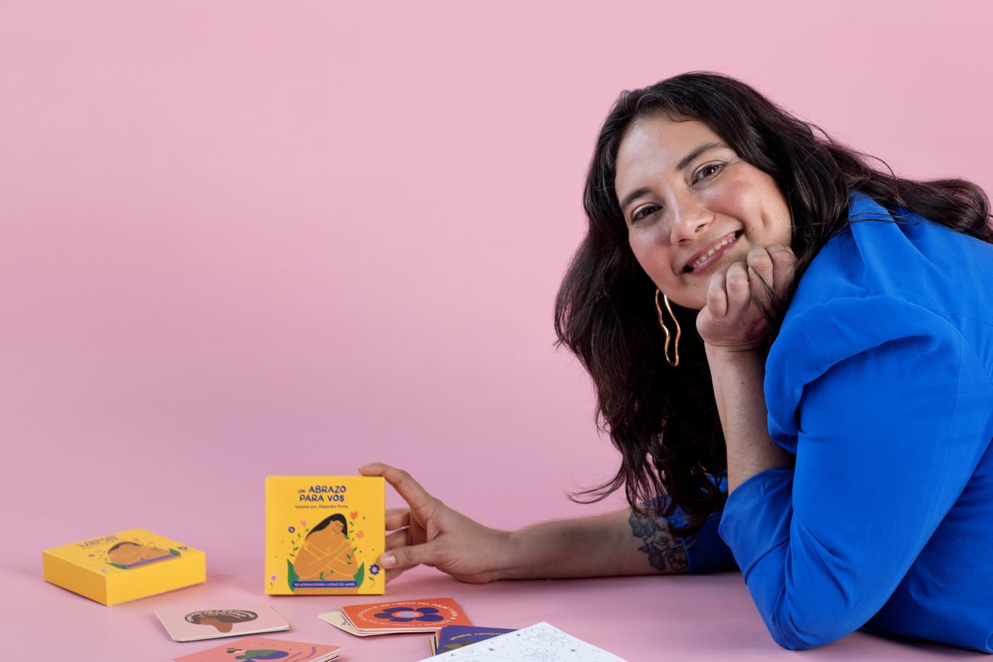 Ale lying on a pink floor with her affirmation cards and coloring book
