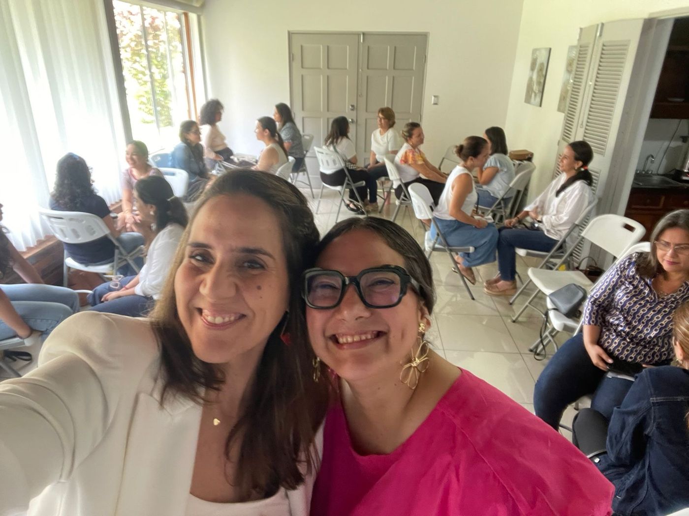 Ale and a co-host smiling in front of a room of workshop participants